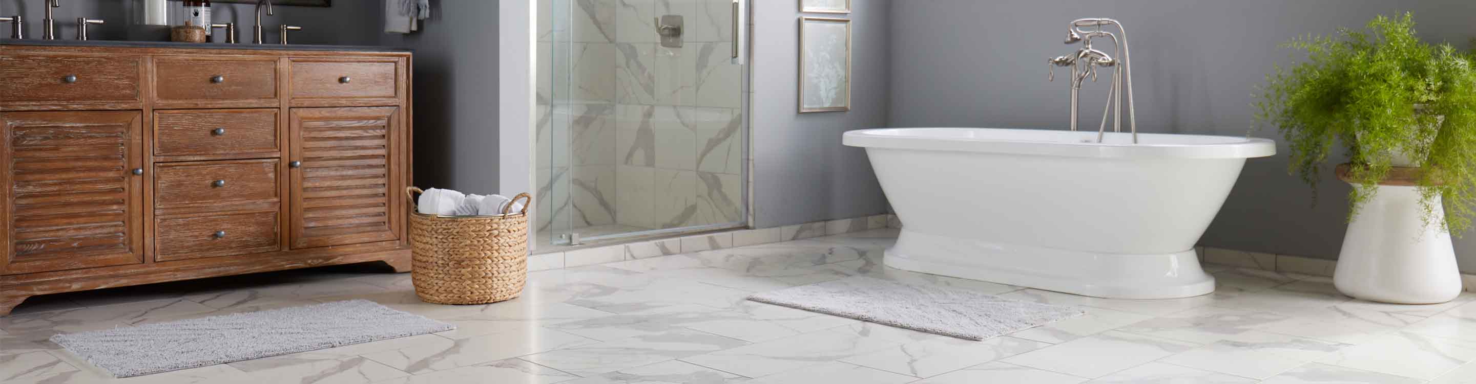 Bathroom with white freestanding bathtub, stone look tile flooring, and brown sink
